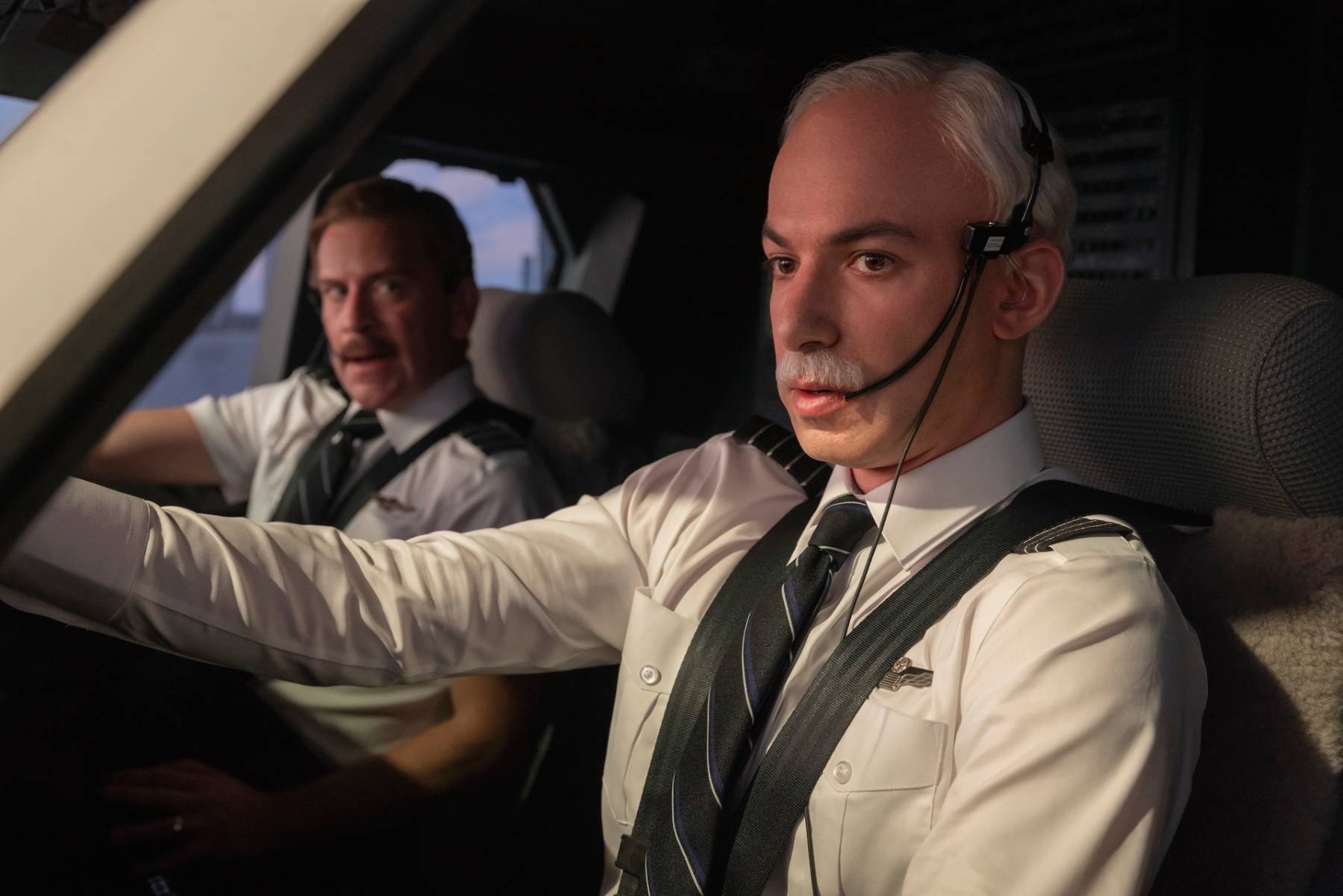 Two men dressed as airline pilots in a cockpit simulator, a scene from The Rehearsal